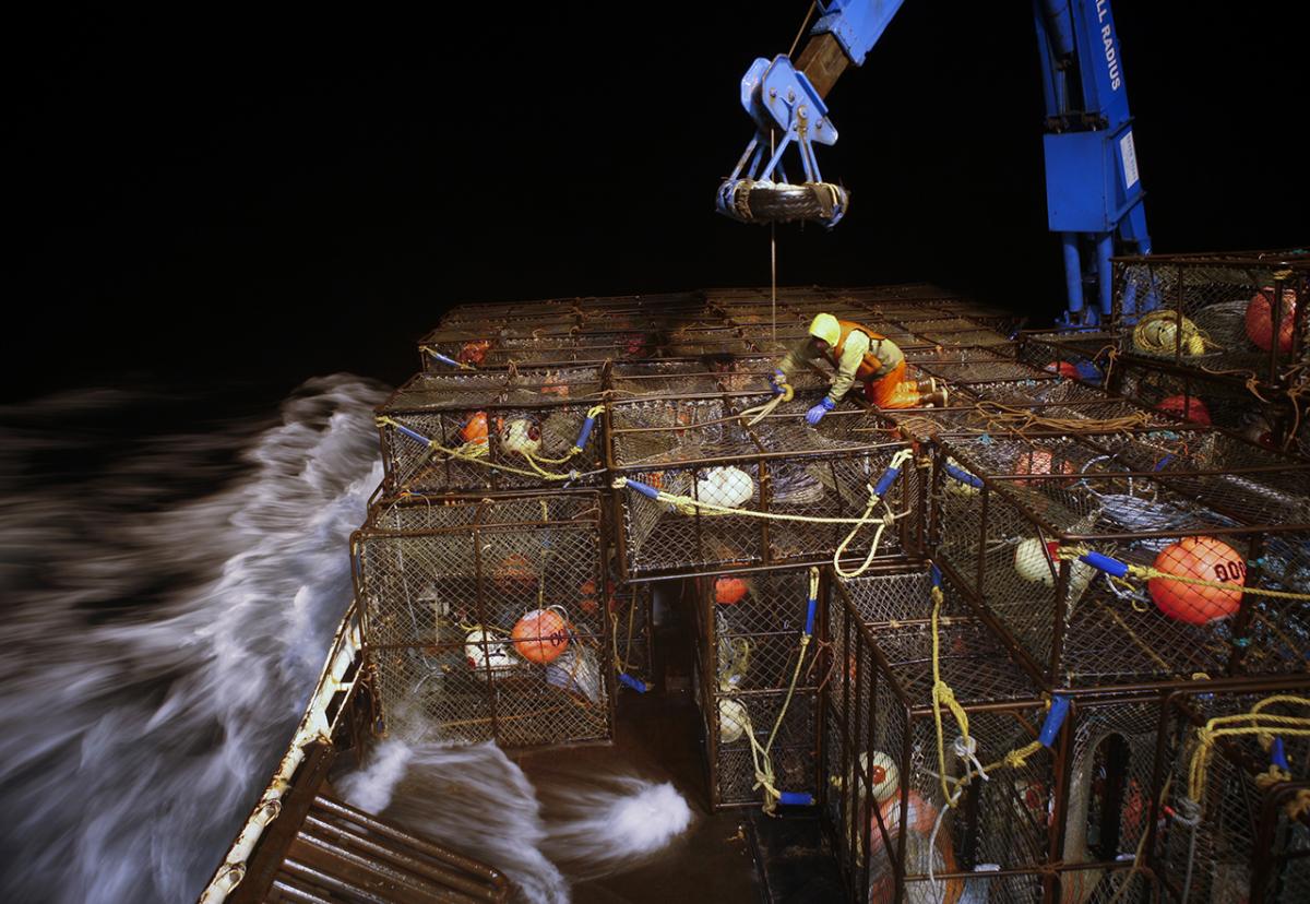 A man stacks lobster pots at night on board a commercial fishing vessel in Alaska