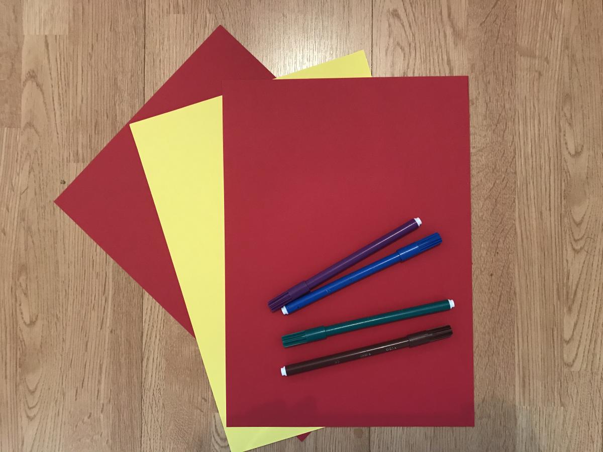 Three pieces of paper, 2 red, 1 yellow. Some pens in various colours.