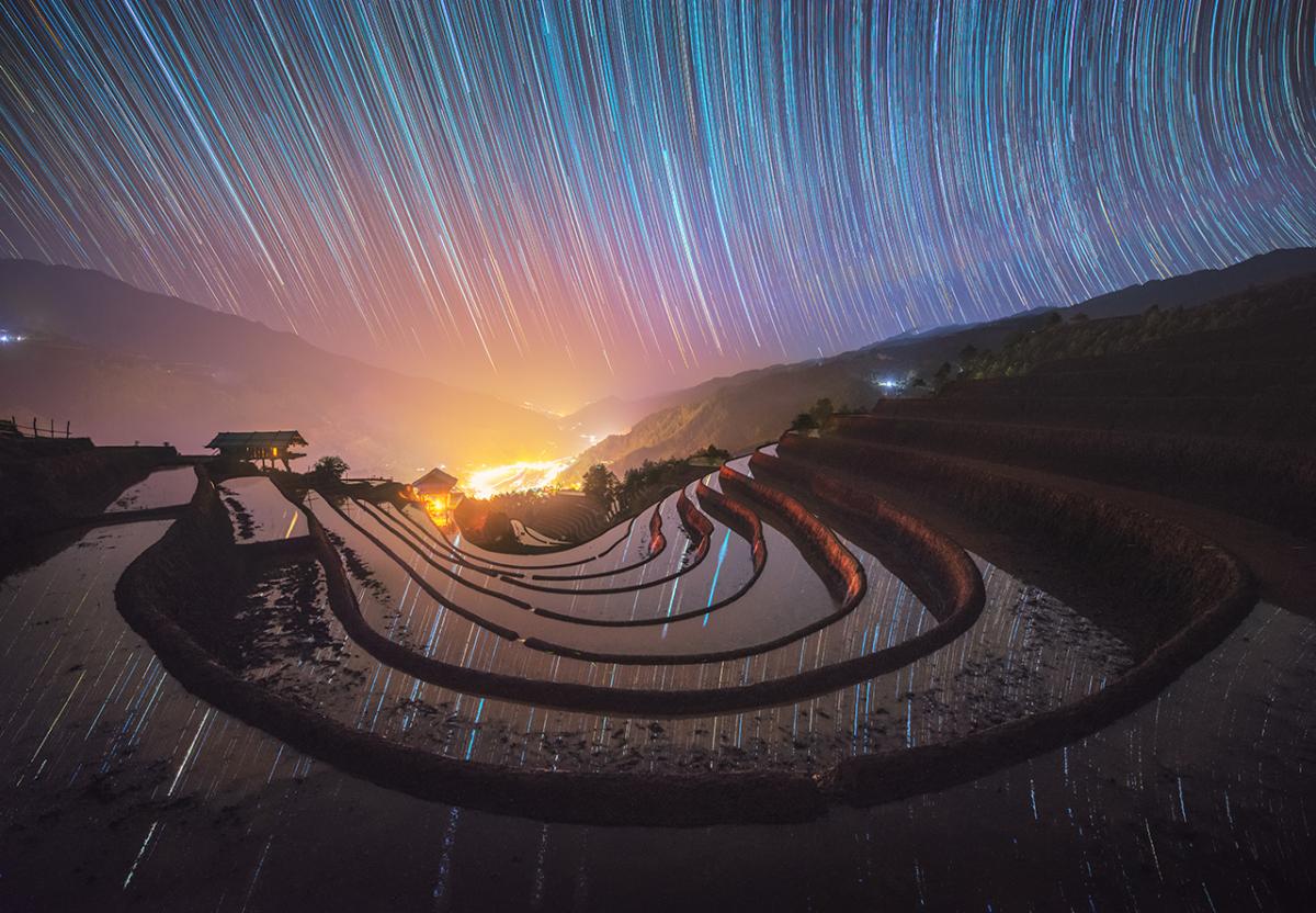 Star trails are reflected in water-filled fields