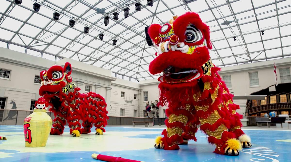Two bright red and yellow 'lions' stand in the National Maritime Museum as part of a traditional Chinese Lion Dance performance