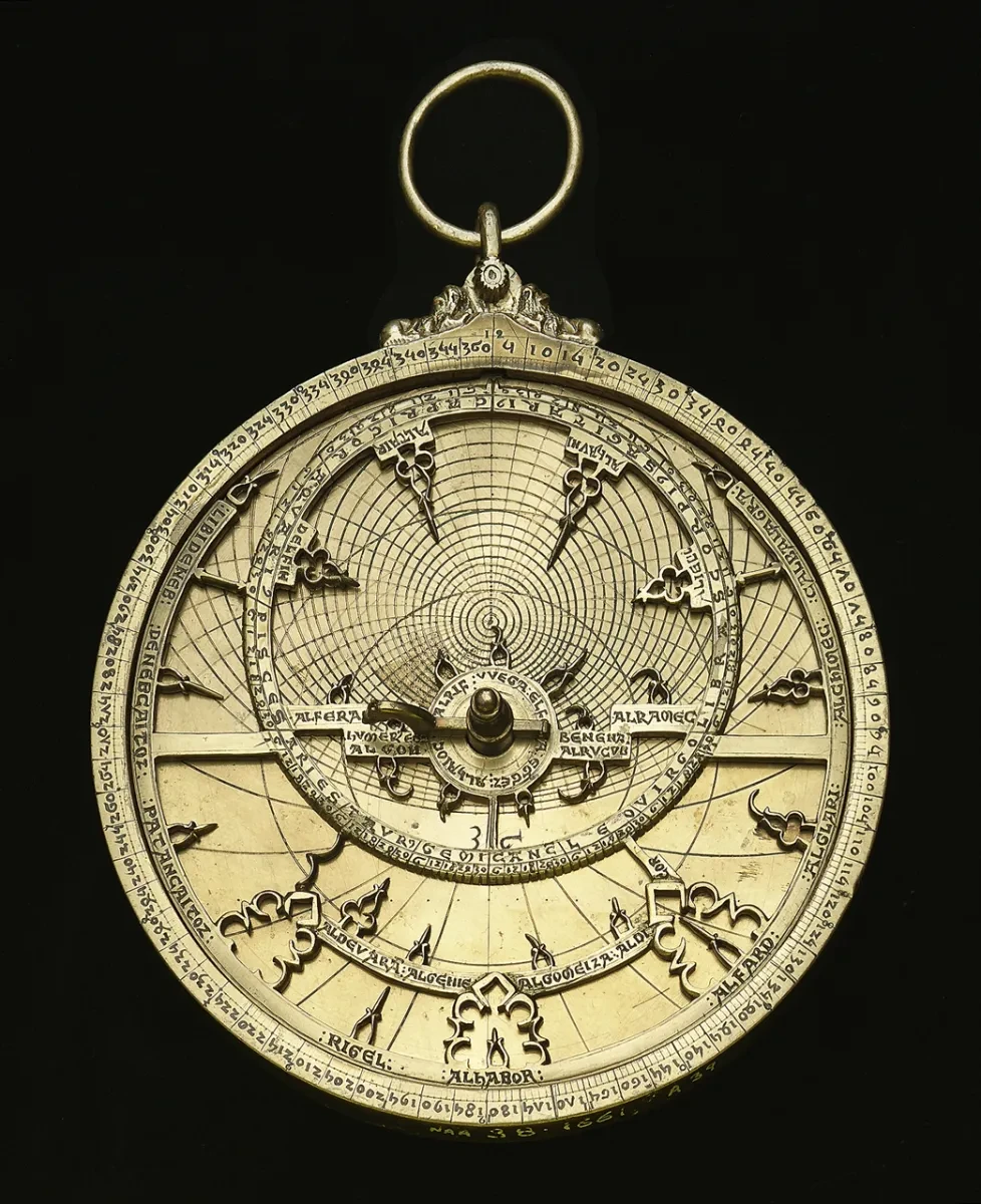 An intricate gold astrolabe on a black background