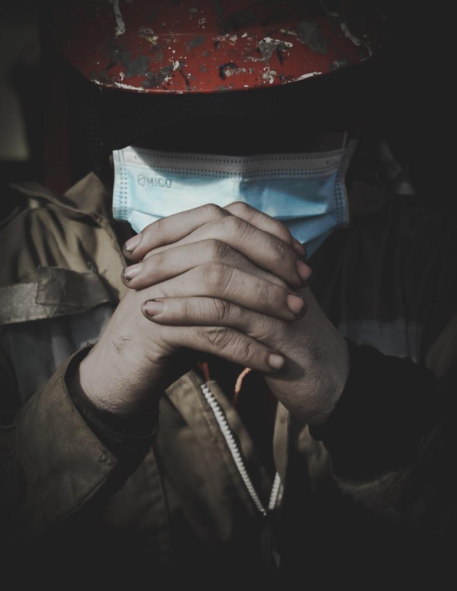 A seafarer wearing a mask holds his hands in prayer
