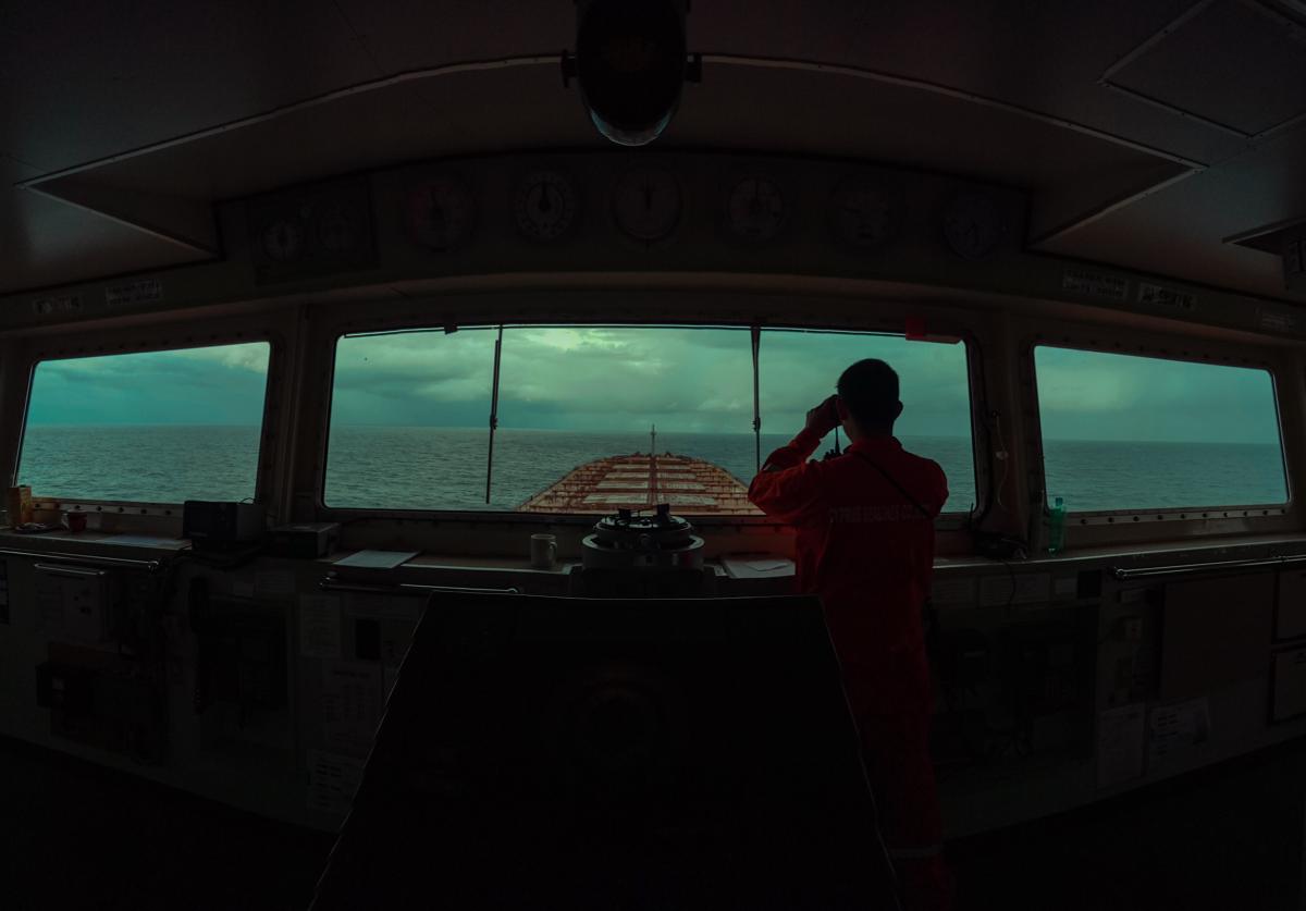 A ship's captain stares out at the sea in front of the boat