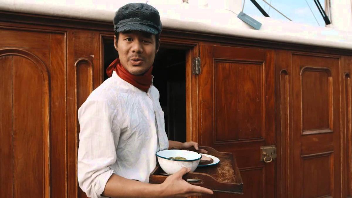 James Robson holding a tray of food emerging from a Cutty Sark cabin.