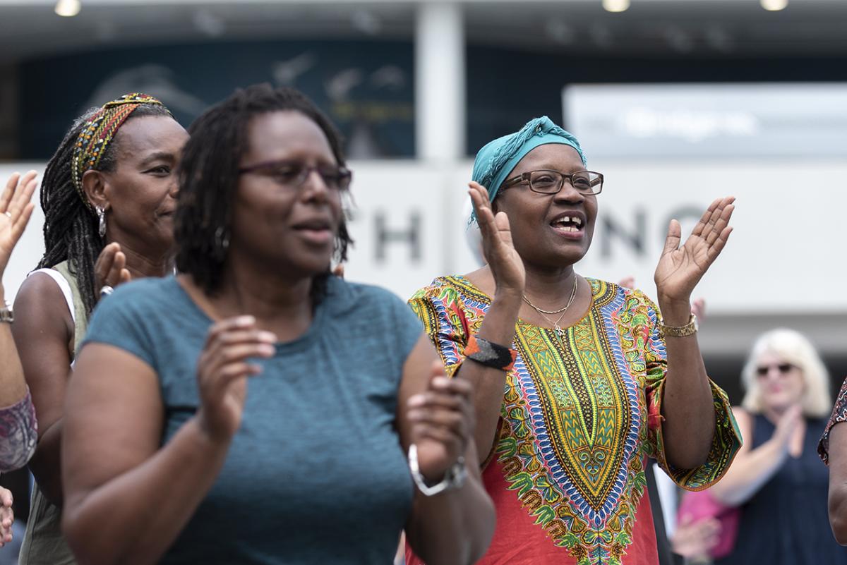 A group of women clap in celebration as they watch a musical performance