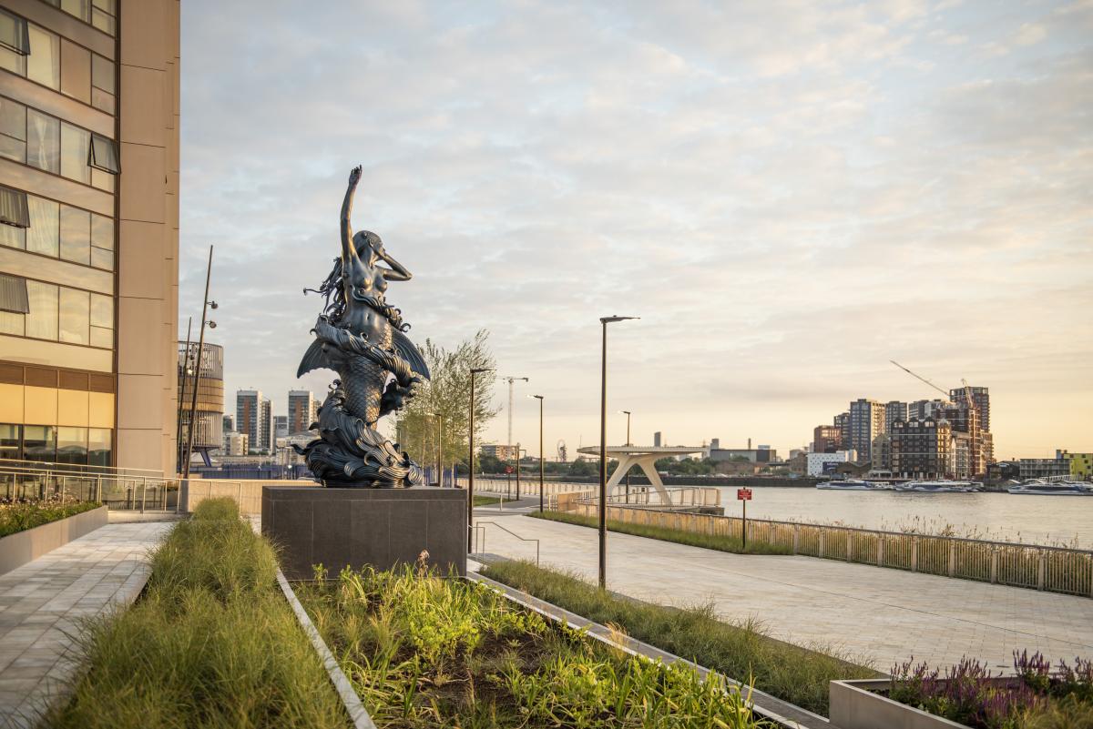 A sculpture of a bronze mermaid stands on Greenwich Peninsula