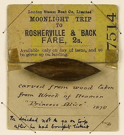 A small wooden boat attached to a ticket. The note reads, 'Carved from wood taken from wreck of steamer Princess Alice'