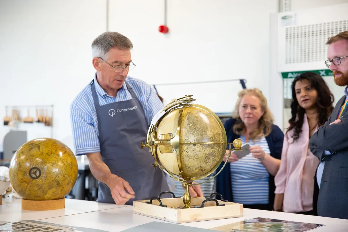 A member of the conservation team shows a tour group a globe
