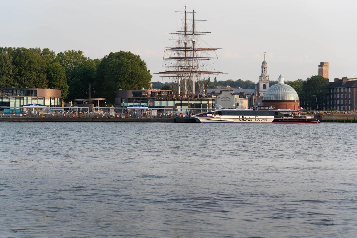 A photograph of the quayside at Greenwich, with a modern ferry service moored in front of the historic ship Cutty Sark