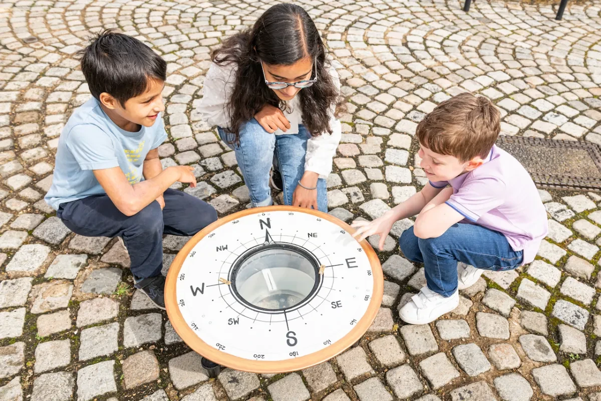 A family gather round a large demonstration compass at the Royal Observatory