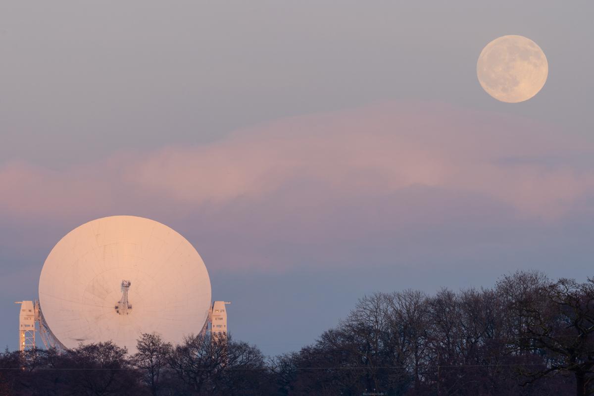 A satellite dish and the Moon in a dusky coloured sky