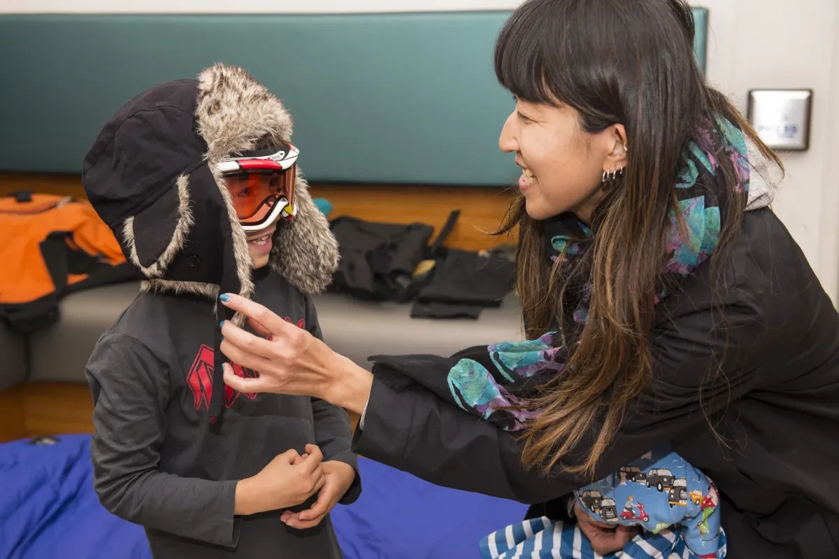 An adult helps a child to get dressed into polar gear
