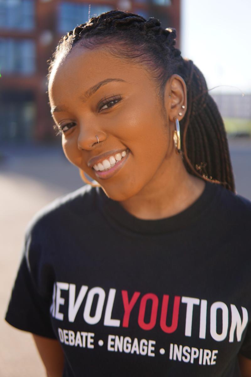 A smiling woman wears a t shirt with Evolyoution written on it