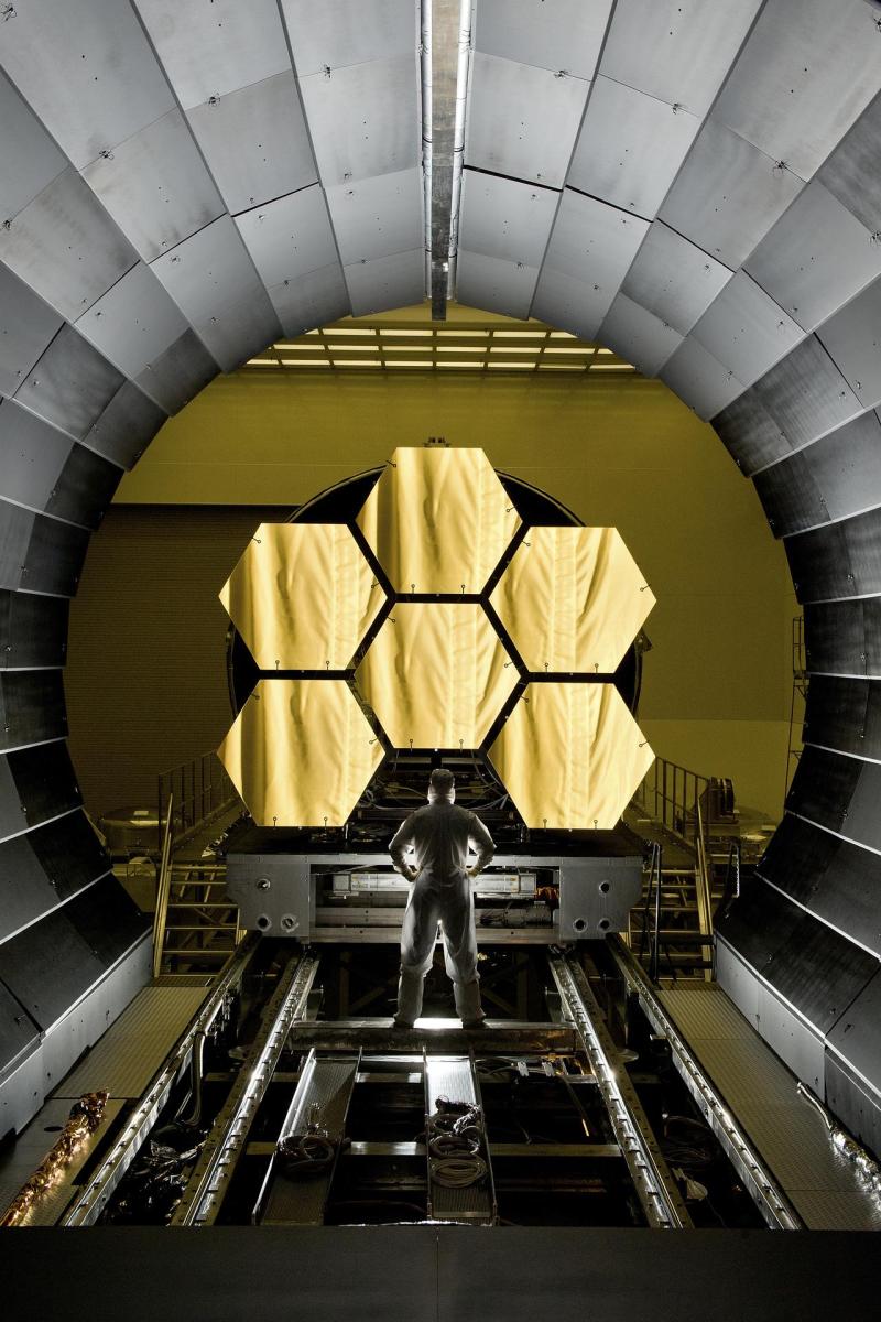 A scientist stands in front of the James Webb Space Telescope during testing
