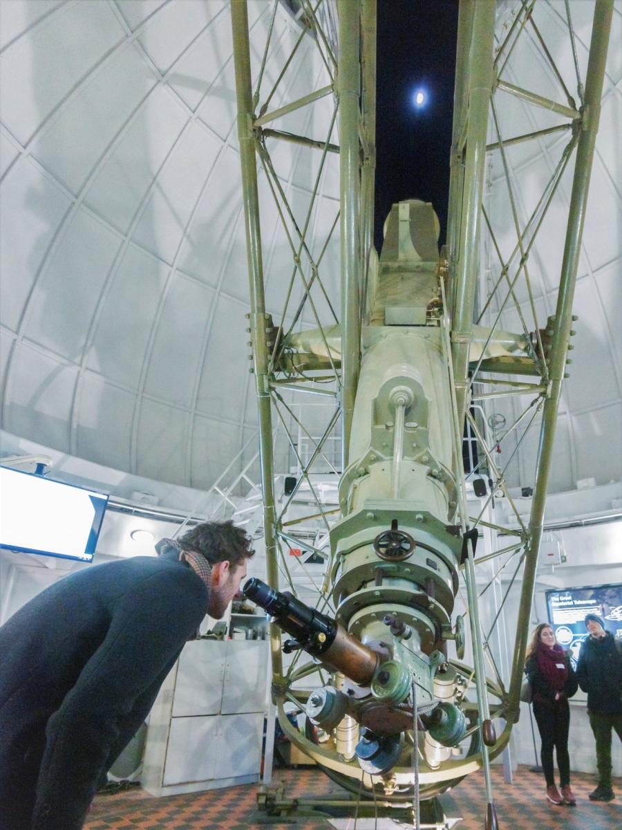 A man looks up at the Moon through an historic telescope at the Royal Observatory