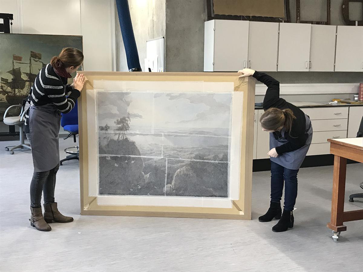 Two conservators examine a painting during a conservation project