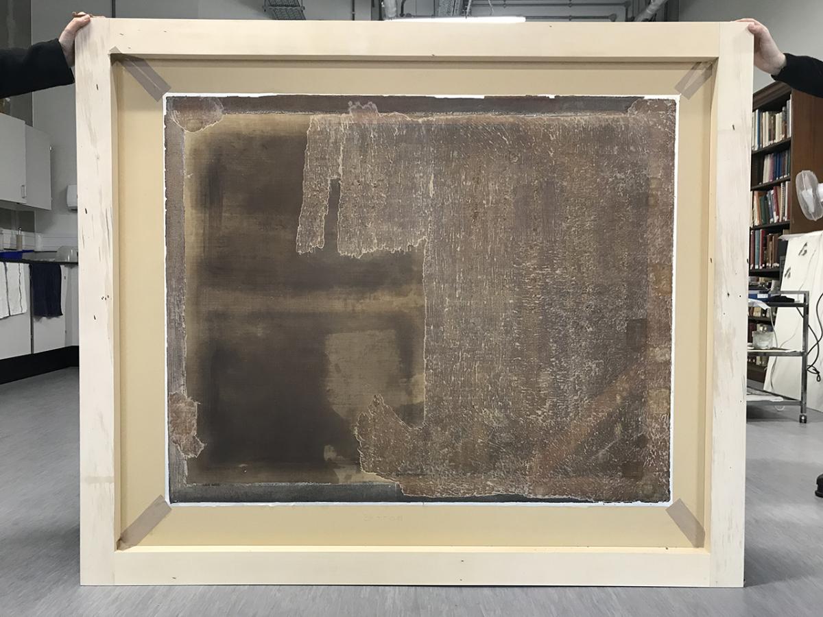 The reverse of a painting part way through a conservation de-lining process
