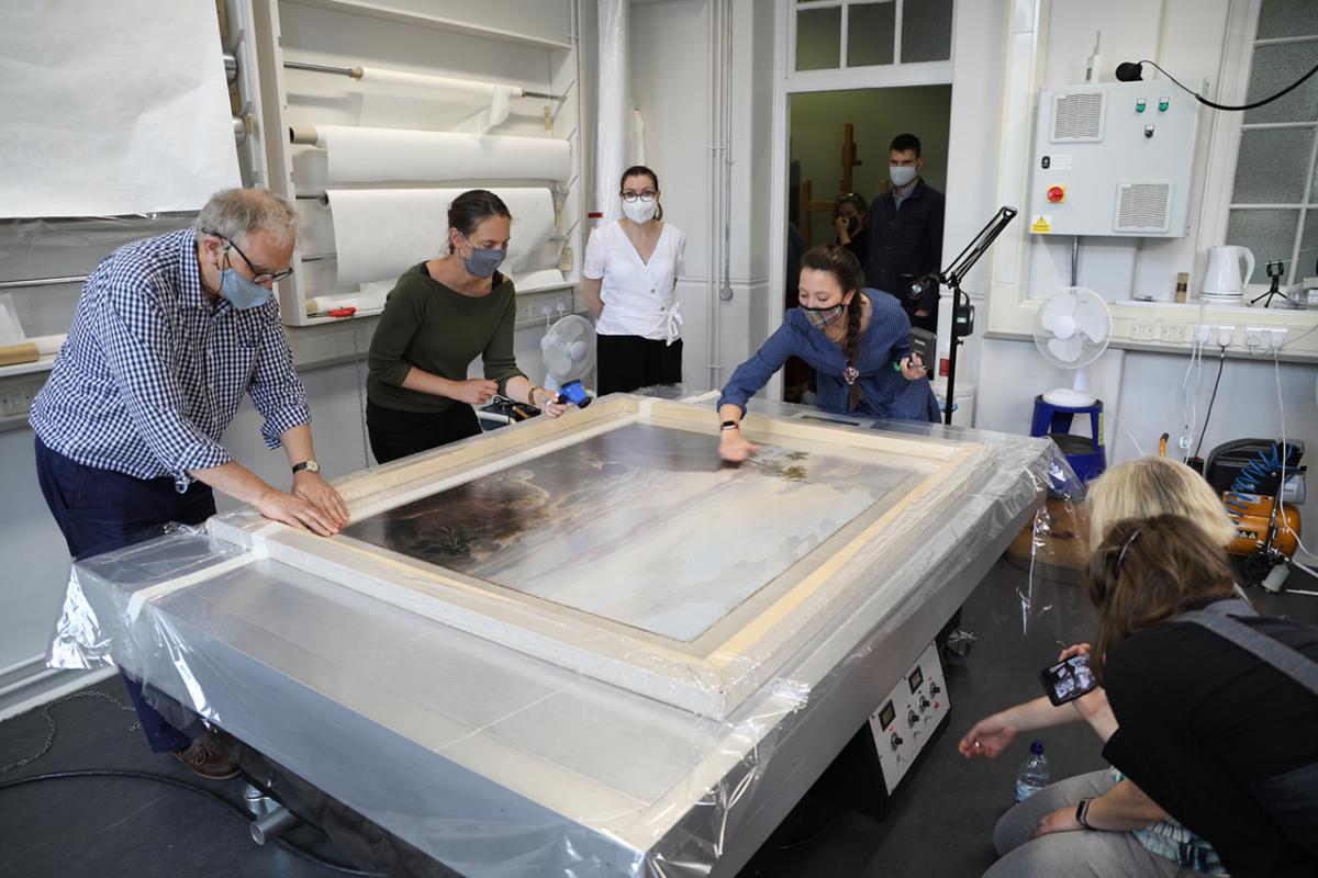 A painting is placed on a vacuum table during a conservation project