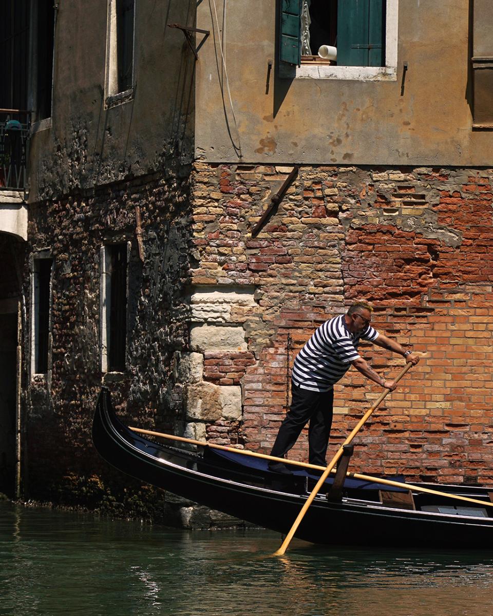 A gondola passing a crumbling brick wall in Venice