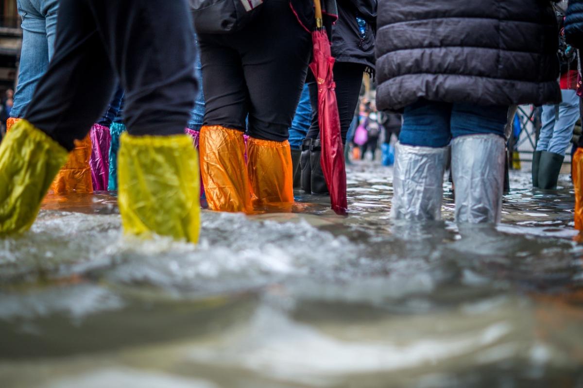 Tourists wearing plastic overshoes try to stay dry in a flooded square in Venice