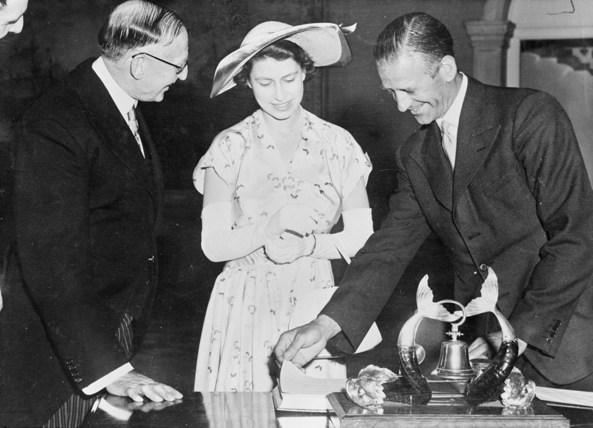 History black and white photograph showing a young Princess Elizabeth  signing the visitors book at the Queen's House in 1951