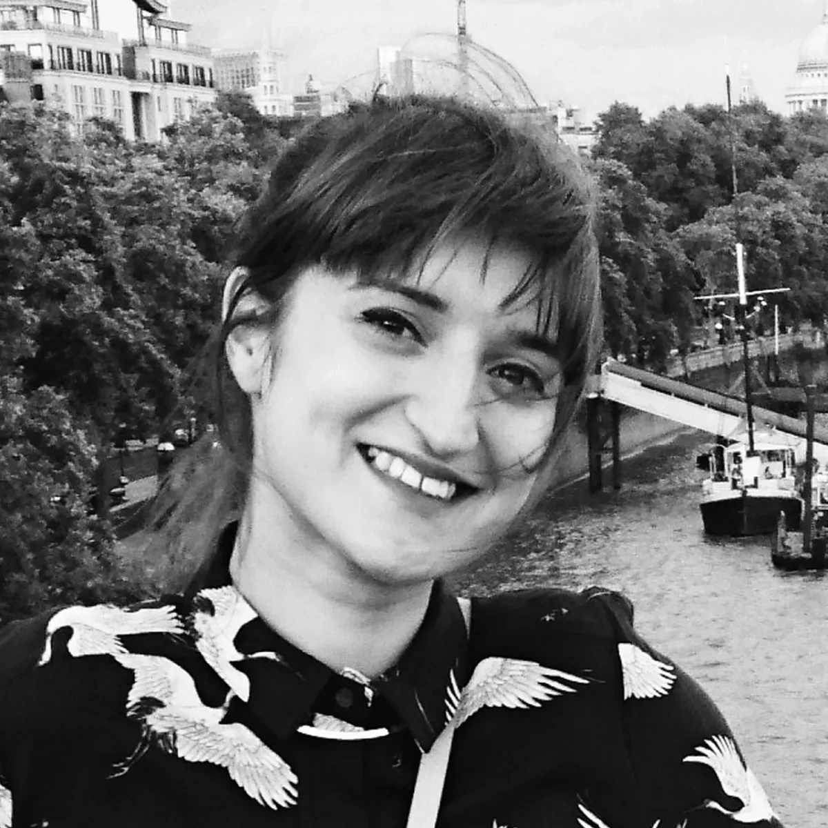 A headshot of the artist Amber Cooper-Davies. The black and white photograph shows her smiling and looking directly at the camera