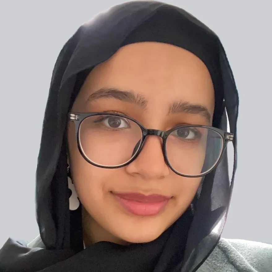 A headshot of the artist Aya Mohamed. She is wearing glasses and a headscarf and looking directly at the camera