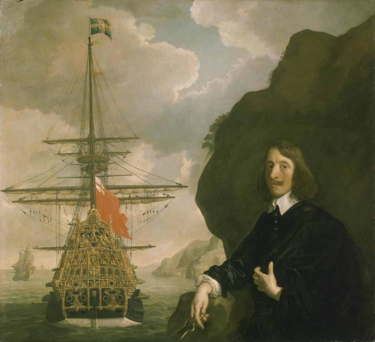 A man stands next to a ship with a golden stern