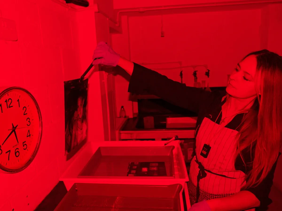A photographer working in a dark room. The light is red thanks to the red light bulb used during developing photographs