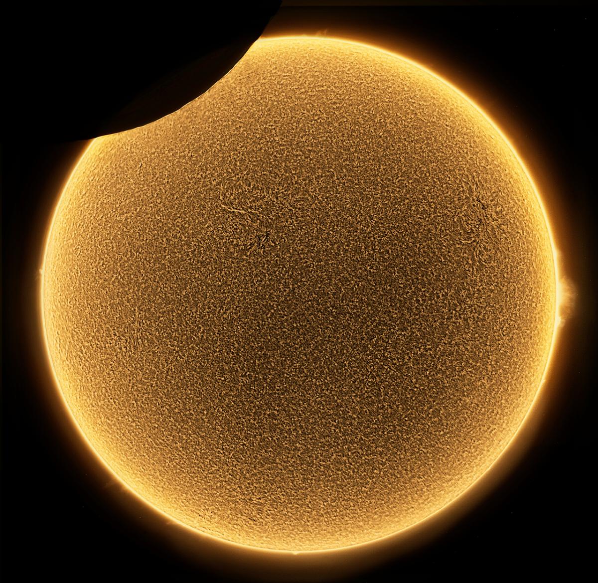 Partial eclipse of the Sun as it reaches its maximum. Central yellow sun with top left section covered by shadow of the Moon