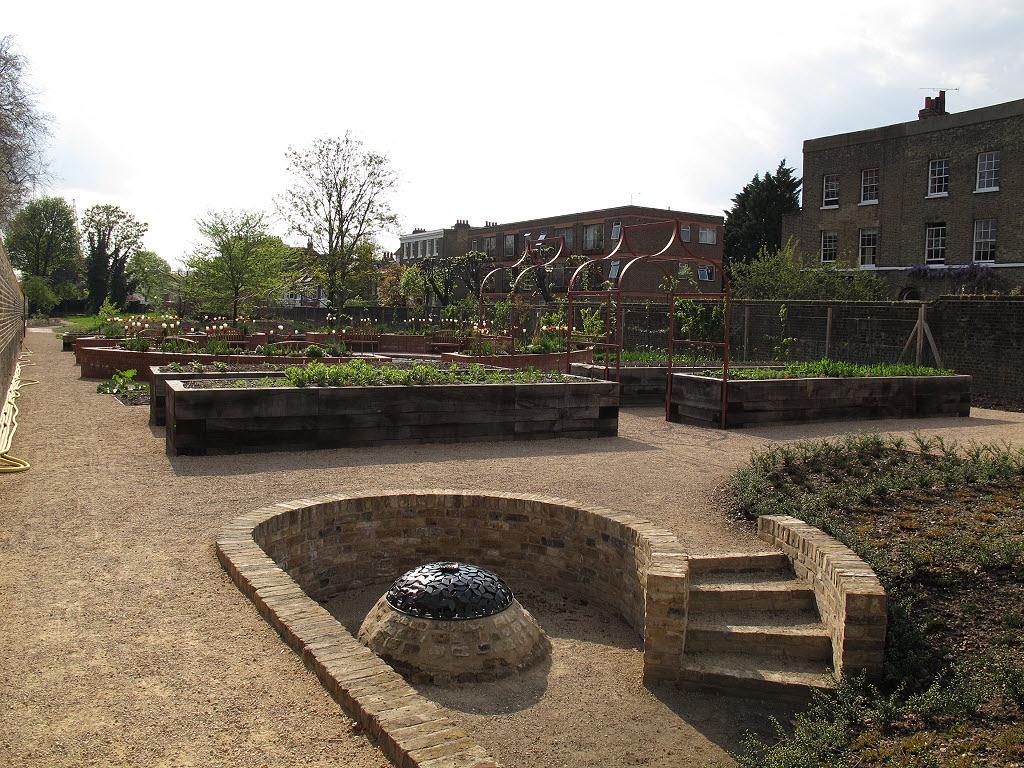 A landscaped garden with raised beds in the centre of the image, and steps and footpaths in the foreground, located in Greenwich Park