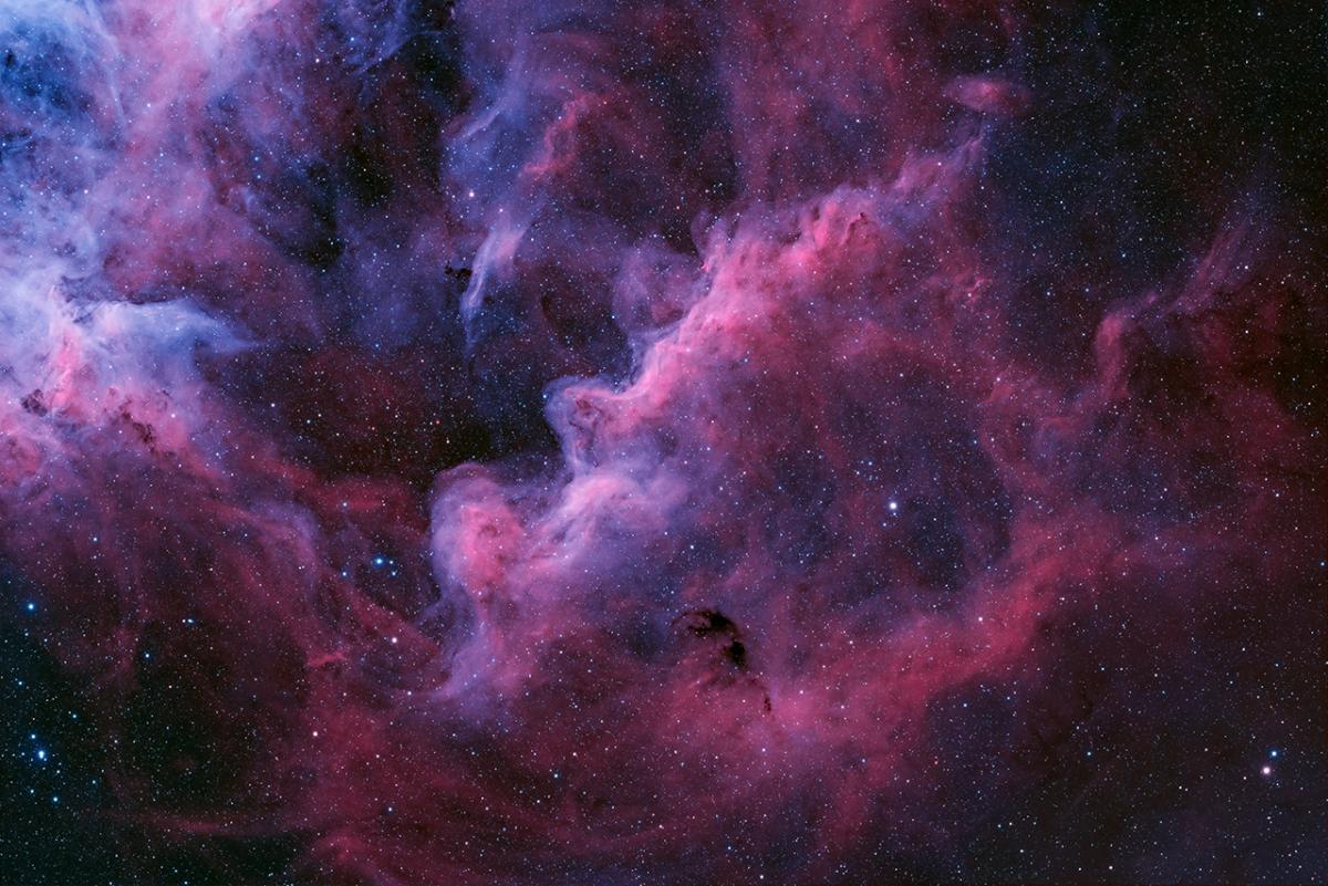 Large clouds of lilac and fuscia pink intersecting against a black sky scattered with stars