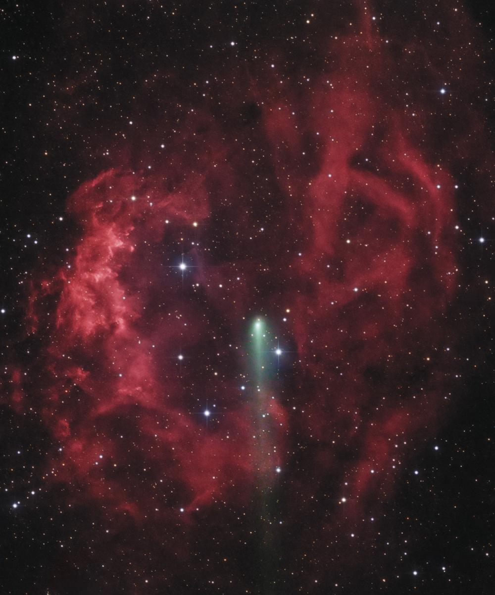 Image of starry black sky with deep and light red nebula over the top. In the middle of the screen is a green shooting comet