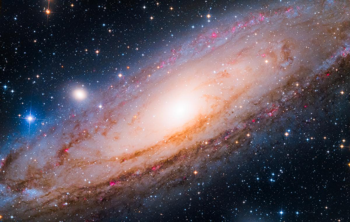 Astrophotograph of the Andromeda Galaxy, showing a spiral of stars tinted from bluey-pink to white at the centre