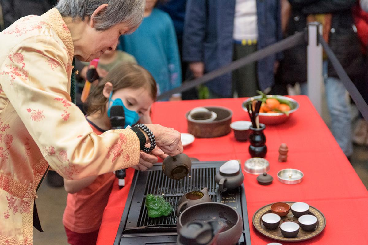 A woman demonstrates a tea ceremony ritual to a young girl during an event at the National Maritime Museum