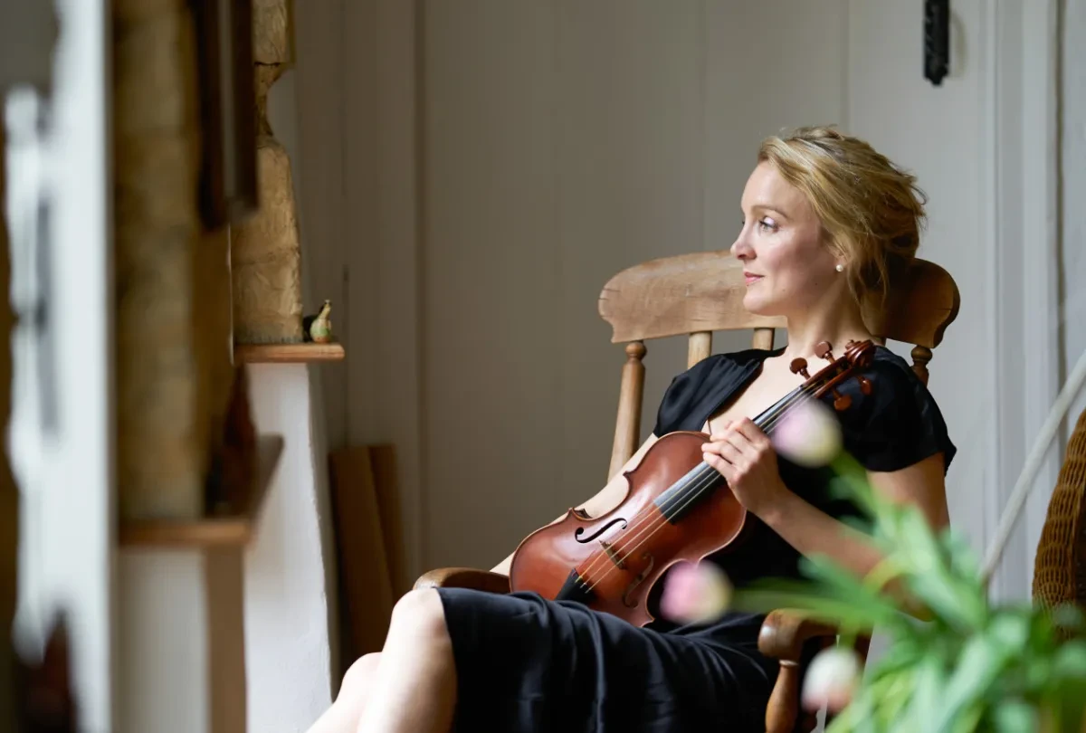 May Robertson sitting, holding her violin.