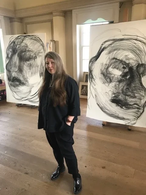 Artist stood in front of two large portraits