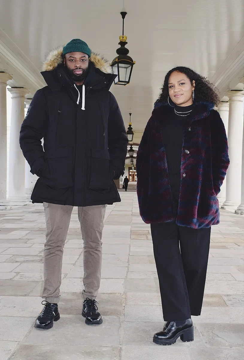 Portrait photograph of The Collective Makers co-founders Lison Sabrina Musset and Joseph Ijoyemi. Joseph is wearing a dark puffer jacket and hat, and Lison a dark purple and red cardigan