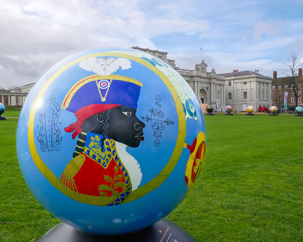 A giant globe on display outside at the National Maritime Museum. On the globe is an artwork featuring a Black man in historic naval uniform