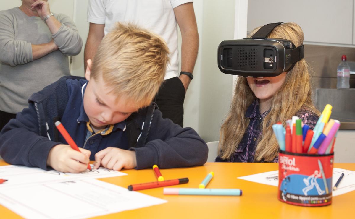 A family workshop at the Royal Observatory, with a boy drawing with a pen and a girl playing with a VR headset