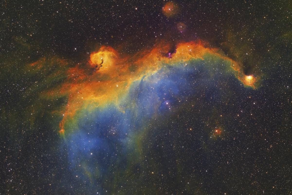 Deep space image showing the  Seagull Nebula, IC 2177, an enormous cloud of ionized hydrogen in the Cosmos. A spectrum of colour created in post-processing creates a stunning rainbow effect