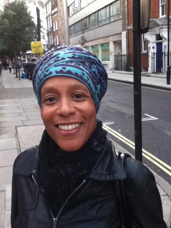 Photo of a black woman with a blue head scarf on a street