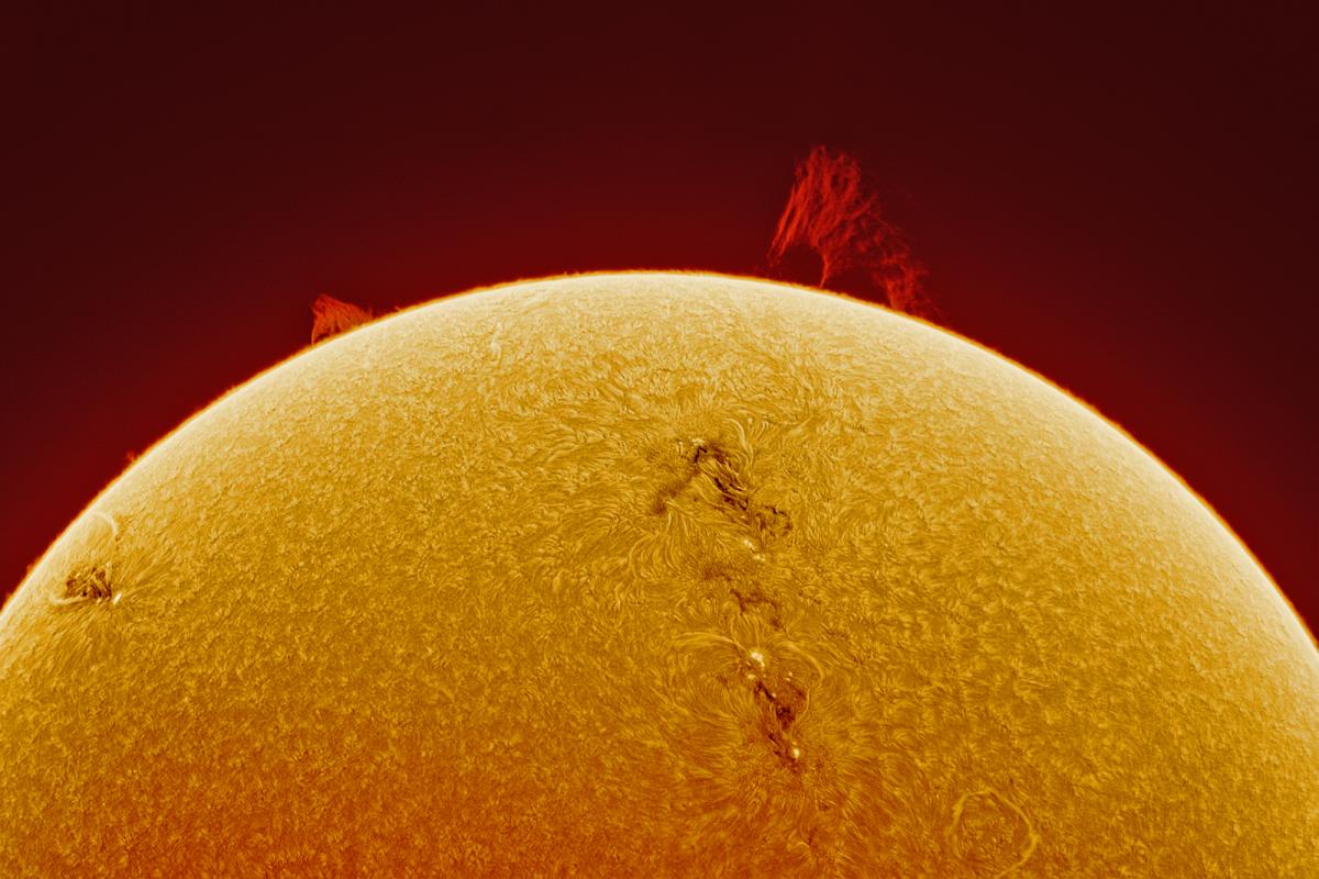 Close up telescope view of part of the Sun's surface. The surface itself is a swirling mix or orange and yellow, almost like waves on a shore. Jets of light appear to be bursting out of the surface