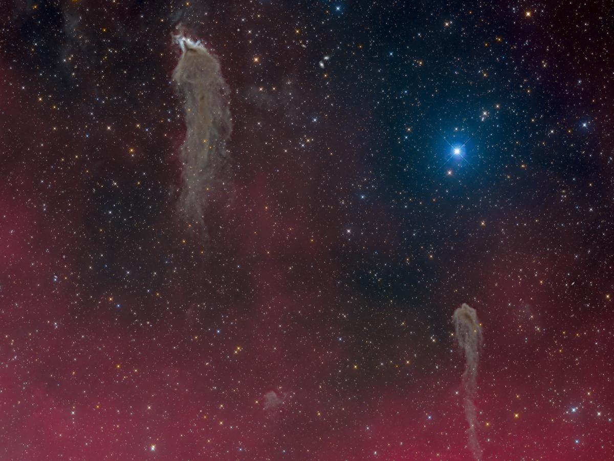 Image showing a black starry night sky which phases into fuscia at the bottom. There is one very bright blue star and there are two wispy ghost-like grey nebulae