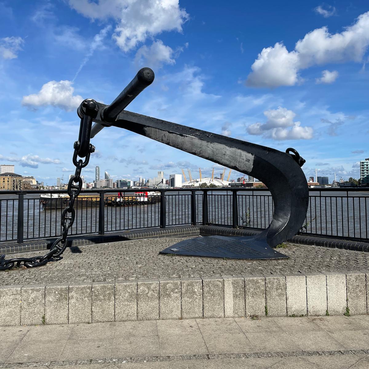 An anchor on display at Anchor Iron Wharf in Greenwich, with the River Thames and O2 in the background