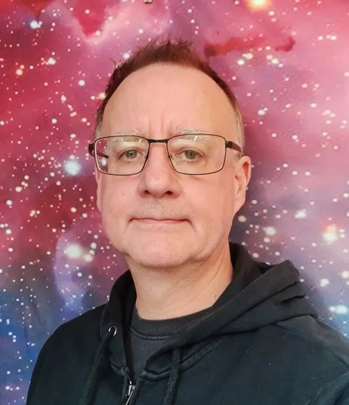 Image of man wearing glasses against an astrophotograph background