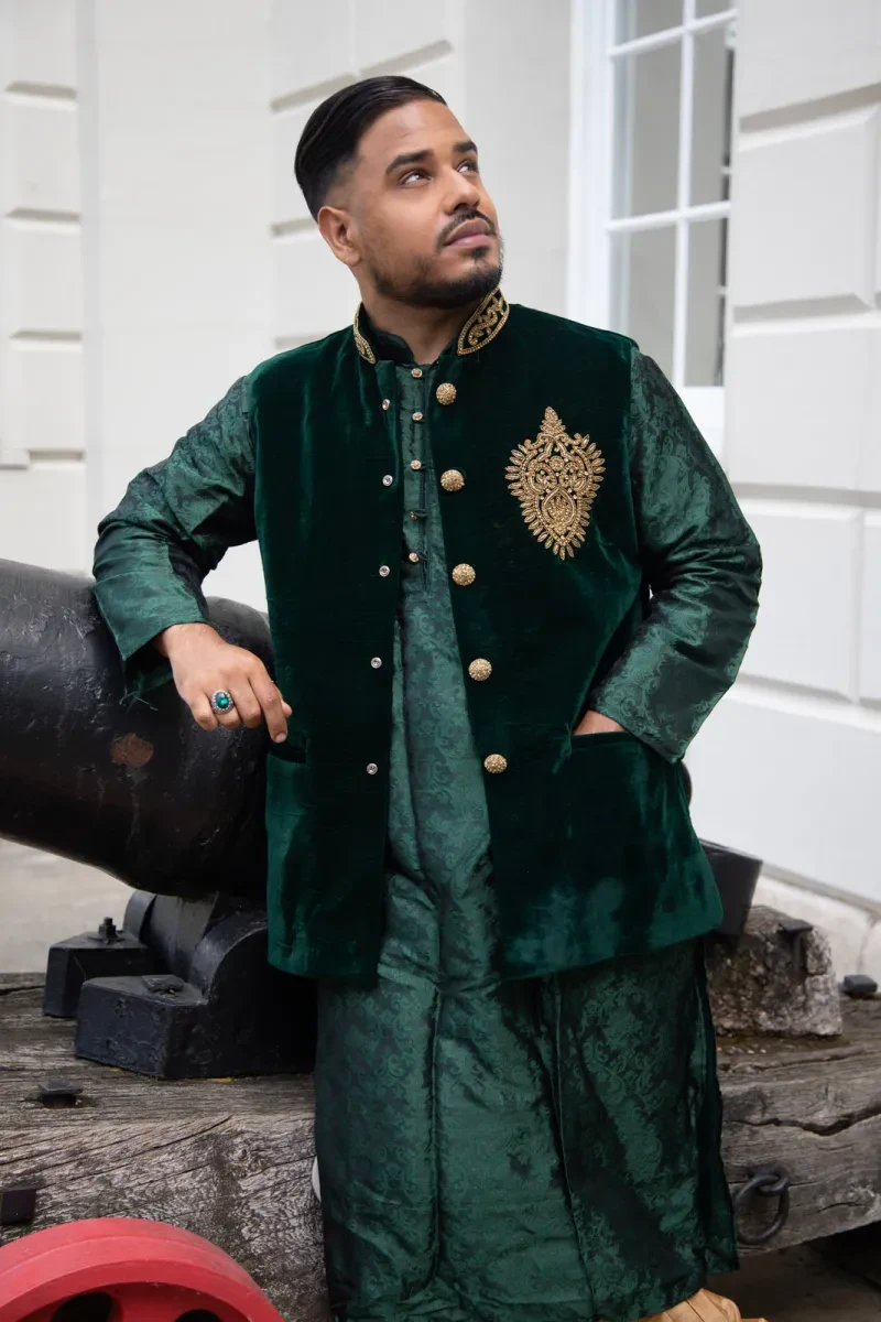 Portrait photograph of a young man wearing a velvet green jacket and silk shirt and trousers