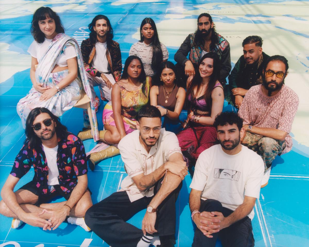 A group portrait photograph of a number of Asian men and women sitting on a giant map. They are all looking up at the camera