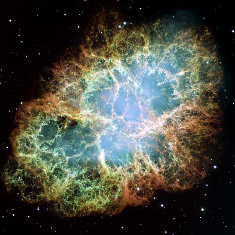 Image of the Crab Nebula, a supernova remnant which looks like an explosion, blue in the middle phasing to green and yellow then red as it moves outwards