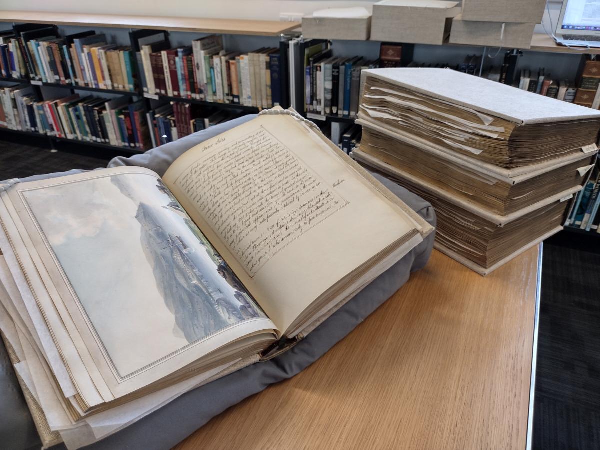 Image of ''Outlines of the Globe' or 'Imaginary World Tour' by Thomas Pennant, a large old volume, on a table within a library